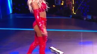 WWE - Carmella in red outfit standing over Sasha Banks