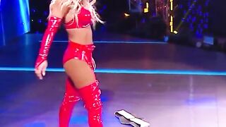 WWE - Carmella in red outfit standing over Sasha Banks