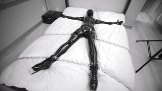 Girl tied and chained on the bed in Latex bondage with vibra