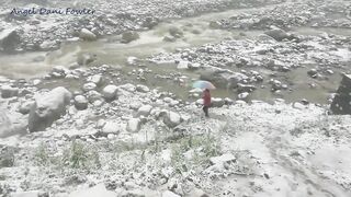 Angel Fowler Walks with Umbrella in Snow next to River