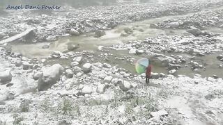 Angel Fowler Walks with Umbrella in Snow next to River