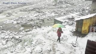 Angel Fowler Walks with Umbrella in Snow next to River