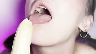 Lucky banana in the mouth of a girl with braces. Eye contact