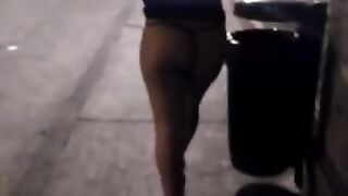 A short girl walking in a dress and showing her thong